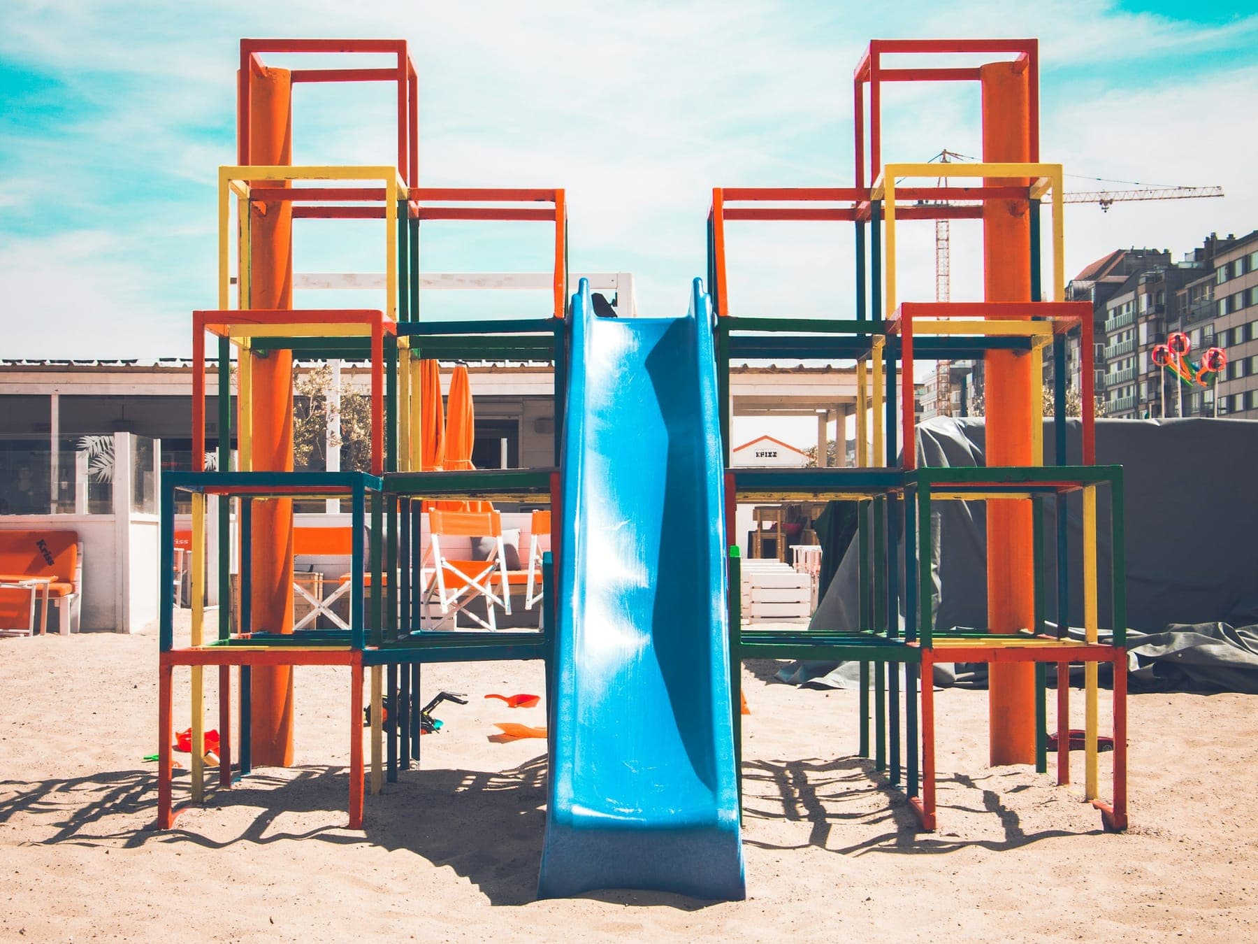 An outdoor climbing frame with a blue slide on a sunny day